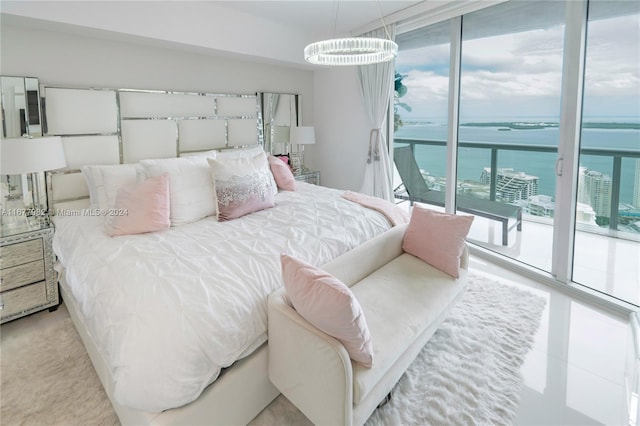 bedroom featuring an inviting chandelier, a water view, multiple windows, and access to exterior