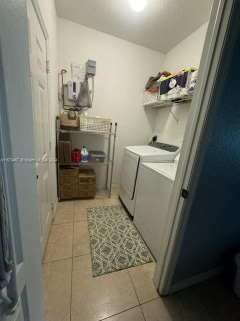 washroom with light tile patterned flooring, independent washer and dryer, and a textured ceiling