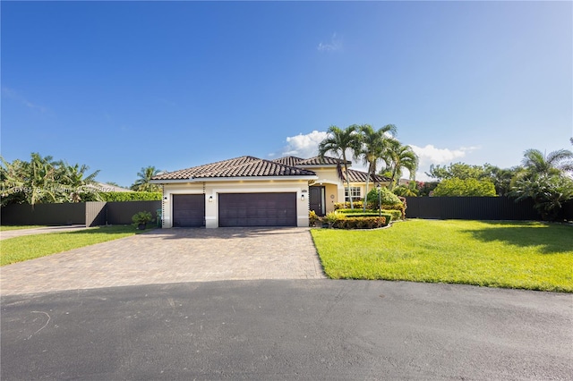 mediterranean / spanish-style house featuring a front yard and a garage