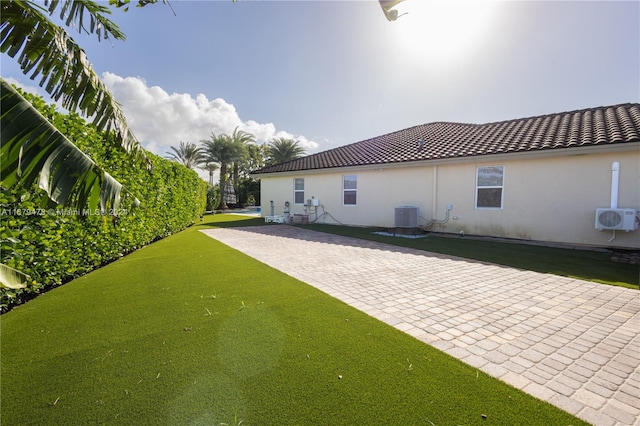 rear view of property featuring a patio area, central AC, a lawn, and ac unit