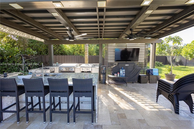 view of patio featuring exterior kitchen, a grill, and ceiling fan