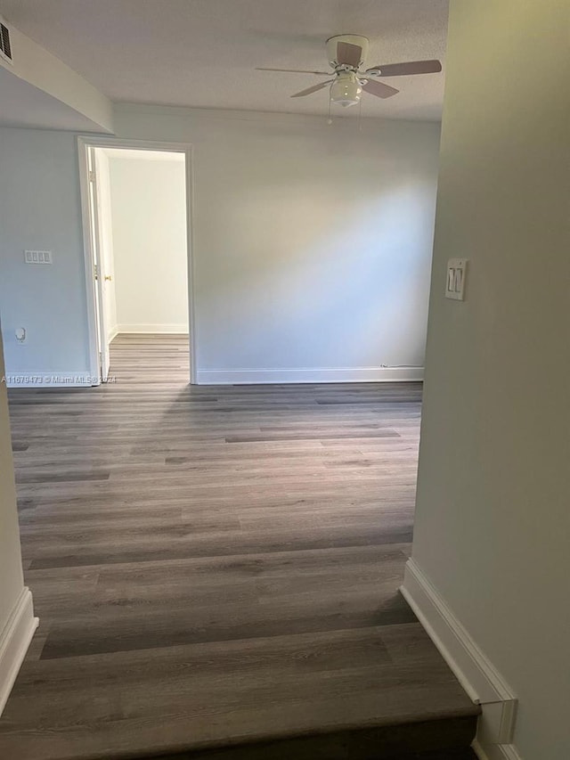 unfurnished room featuring dark wood-type flooring and ceiling fan