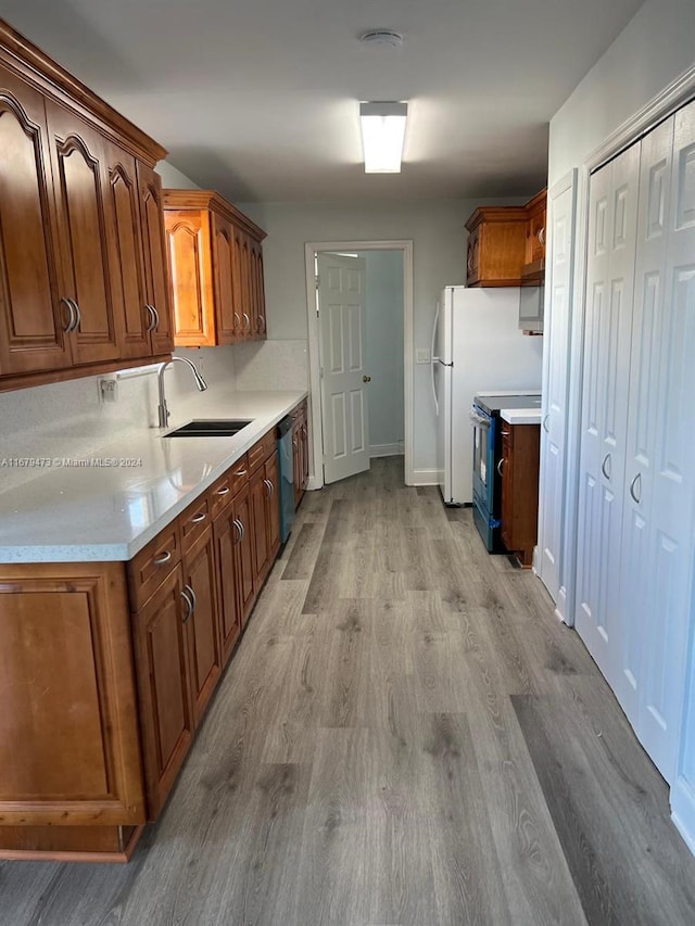 kitchen with black electric range oven, sink, light wood-type flooring, and dishwasher