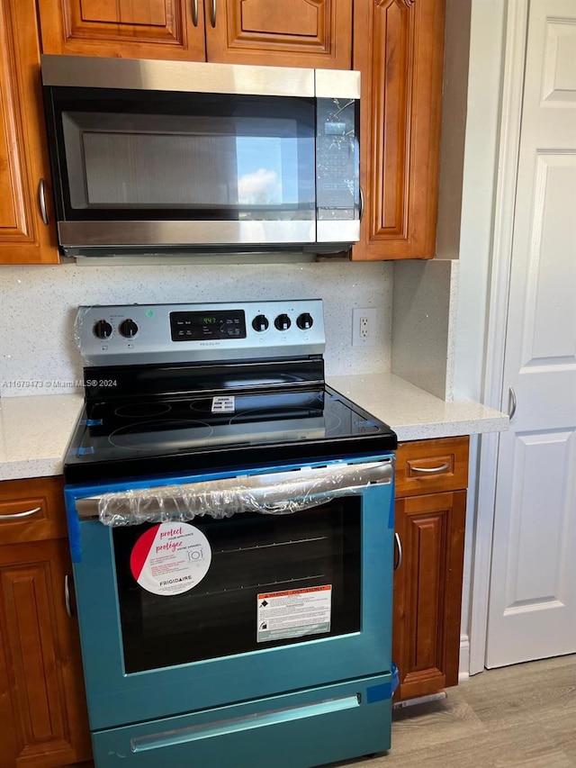 kitchen with decorative backsplash, light hardwood / wood-style flooring, and stainless steel appliances