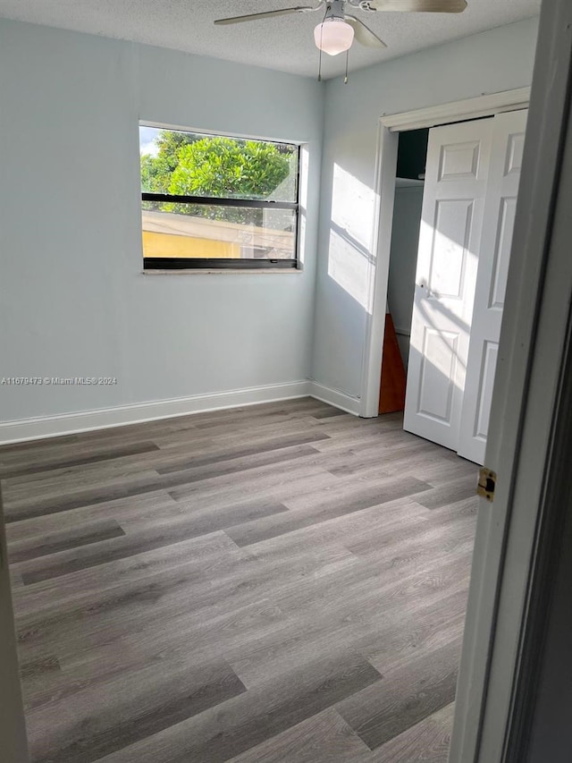 spare room featuring a textured ceiling, light wood-type flooring, and ceiling fan