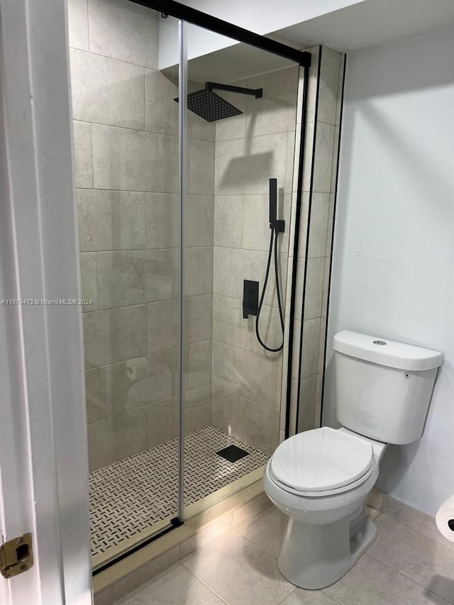 bathroom featuring toilet, tile patterned flooring, and an enclosed shower