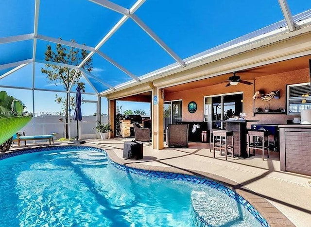 view of pool with an outdoor bar, a lanai, a patio, and ceiling fan