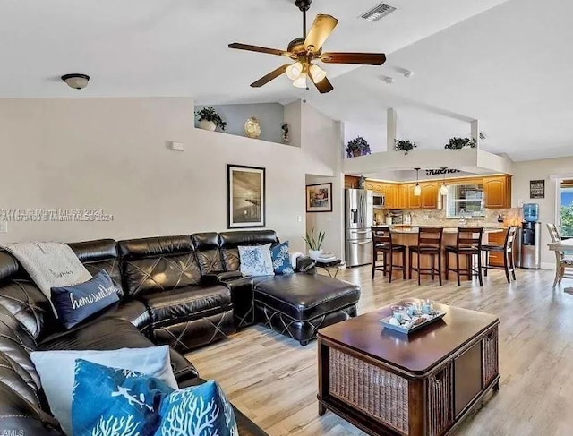 living room with light hardwood / wood-style flooring, high vaulted ceiling, and ceiling fan