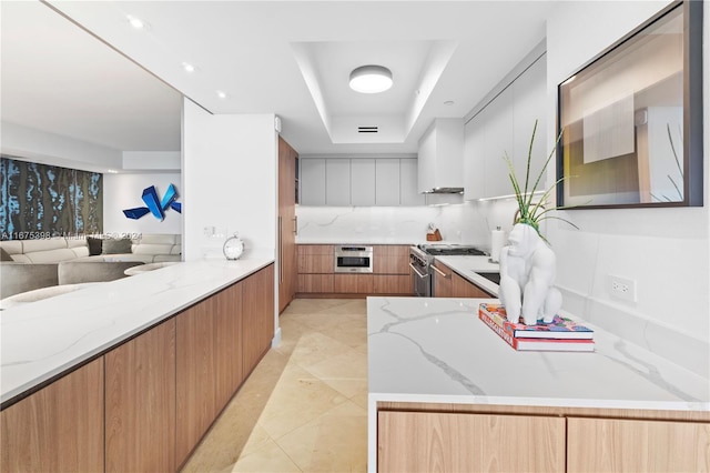 kitchen with a raised ceiling, light stone countertops, stainless steel range, white cabinetry, and heating unit