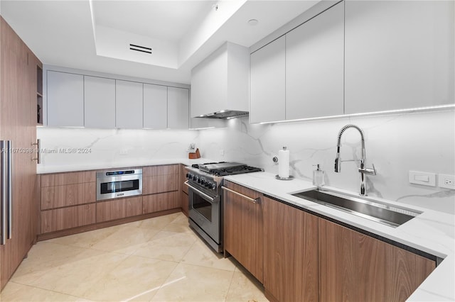 kitchen featuring sink, tasteful backsplash, light tile patterned flooring, white cabinets, and appliances with stainless steel finishes