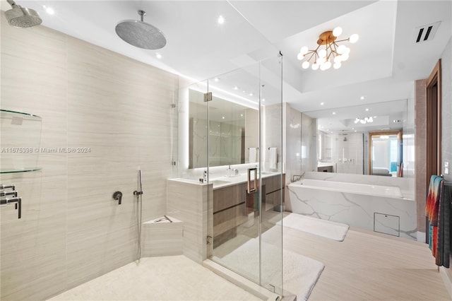 bathroom featuring vanity, independent shower and bath, and a notable chandelier