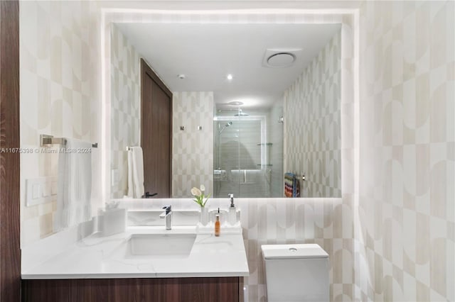 bathroom featuring vanity, a shower with shower door, tile walls, and toilet