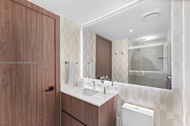 bathroom featuring vanity, a shower with shower door, tile walls, and toilet