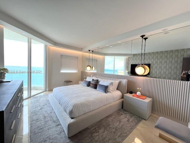 bedroom featuring access to outside, a water view, and multiple windows