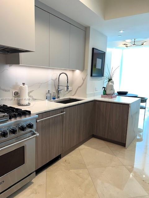 kitchen featuring dark brown cabinetry, high end range, sink, and tasteful backsplash