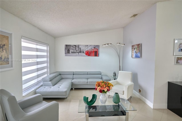 tiled living room featuring a textured ceiling, plenty of natural light, and vaulted ceiling