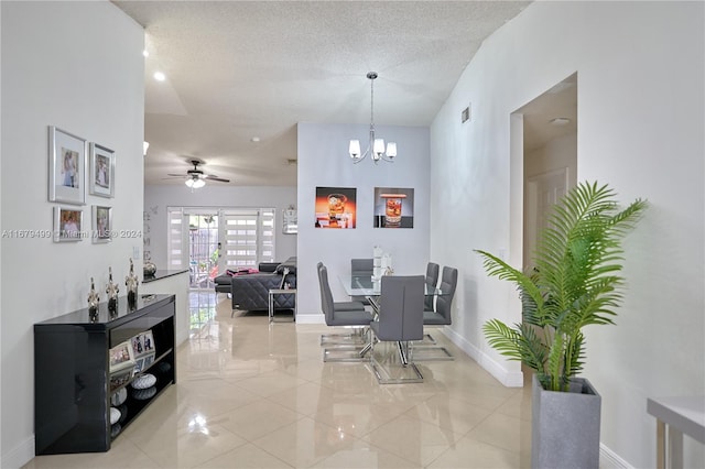 dining space featuring a textured ceiling and ceiling fan with notable chandelier