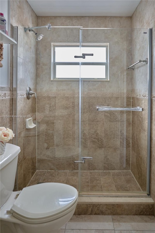 bathroom with toilet, a healthy amount of sunlight, and a shower with shower door