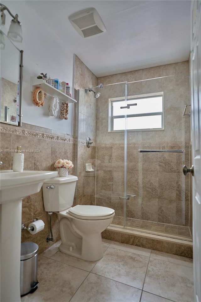 bathroom featuring tile walls, tile patterned flooring, toilet, and walk in shower