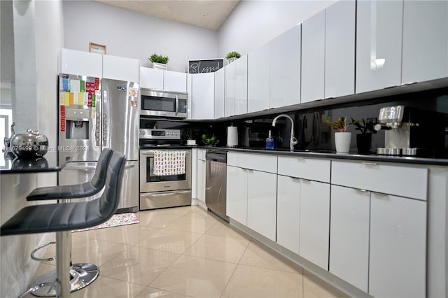 kitchen featuring light tile patterned flooring, white cabinetry, stainless steel appliances, and sink