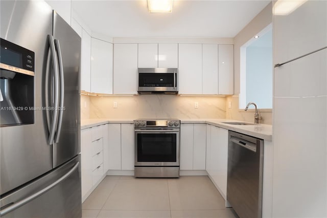 kitchen featuring sink, white cabinetry, light tile patterned floors, decorative backsplash, and appliances with stainless steel finishes