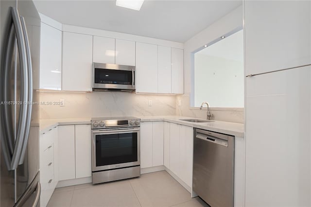 kitchen featuring stainless steel appliances, light tile patterned floors, white cabinets, backsplash, and sink