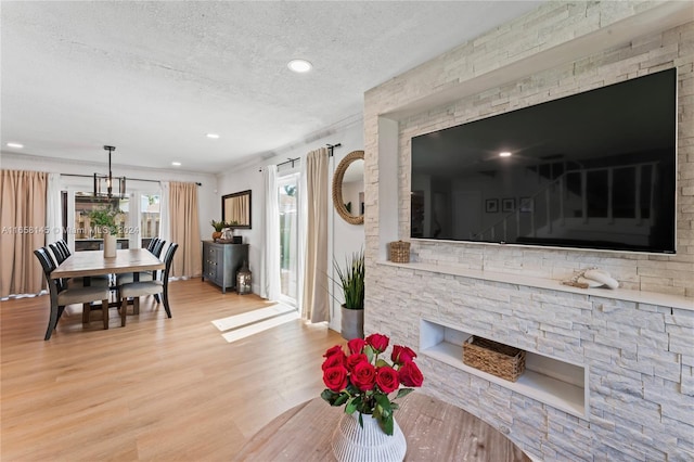 living room featuring crown molding, a textured ceiling, and light hardwood / wood-style floors