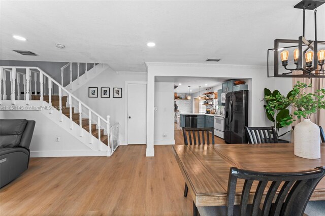 dining space featuring a notable chandelier, ornamental molding, and light wood-type flooring