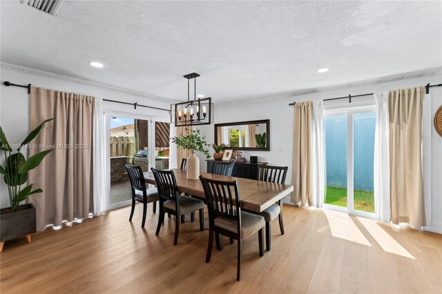 dining space with a notable chandelier, wood-type flooring, and a textured ceiling