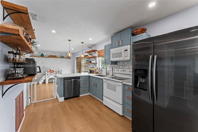 kitchen with appliances with stainless steel finishes, sink, kitchen peninsula, light hardwood / wood-style floors, and decorative light fixtures