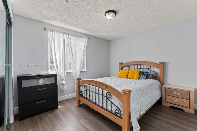 bedroom with a textured ceiling and dark hardwood / wood-style floors