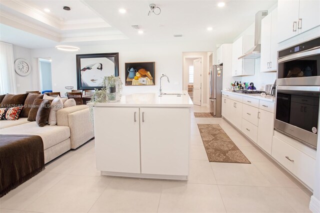 kitchen featuring appliances with stainless steel finishes, white cabinetry, a kitchen island with sink, light tile patterned flooring, and sink