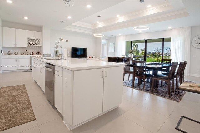 kitchen featuring white cabinetry, a tray ceiling, sink, and a center island with sink