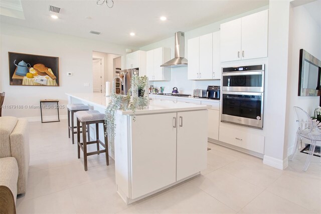 4527 Blessed Place Dr, Oakland Park, FL 33309 - kitchen with wall chimney range hood, stainless steel appliances, a large island, white cabinets, and a kitchen breakfast bar