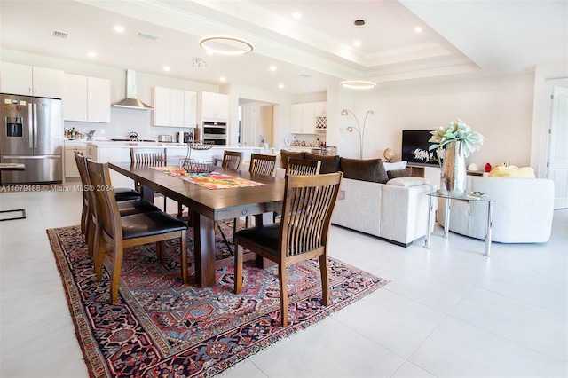 tiled dining area featuring crown molding and a tray ceiling