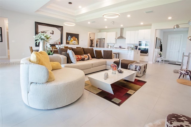 living area featuring baseboards, visible vents, a tray ceiling, crown molding, and recessed lighting