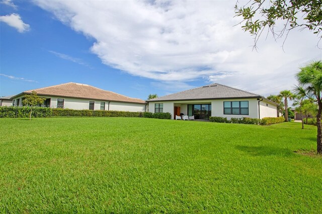 back of house with a lawn and stucco siding