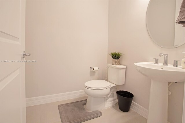 bathroom featuring toilet, sink, and tile patterned flooring