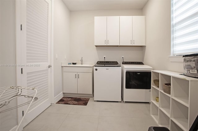 clothes washing area featuring cabinet space, baseboards, washer and dryer, a sink, and light tile patterned flooring