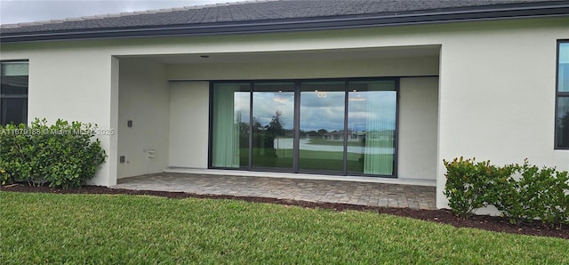 rear view of property featuring a patio area, a yard, and stucco siding