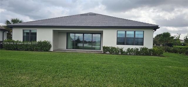 rear view of property featuring stucco siding and a yard