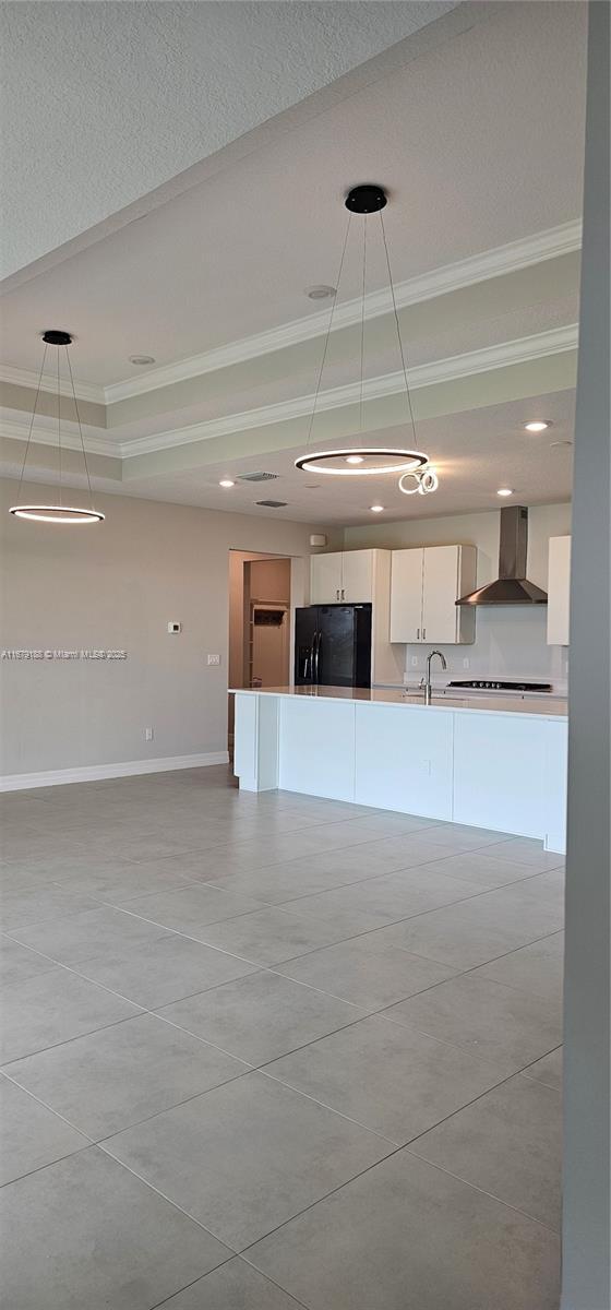 4527 Blessed Place Dr, Oakland Park, FL 33309 - kitchen featuring freestanding refrigerator, wall chimney exhaust hood, crown molding, white cabinets, and decorative light fixtures