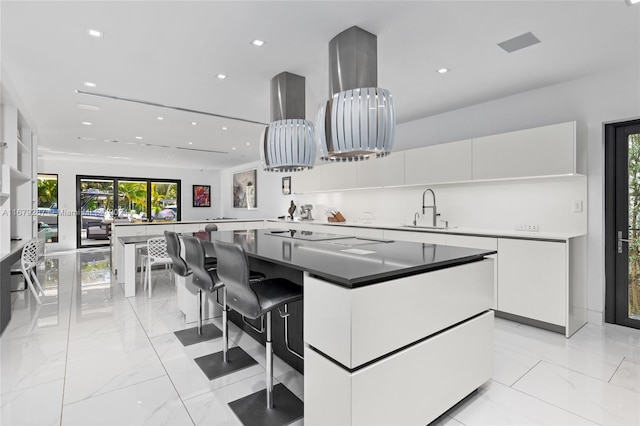 kitchen featuring sink, a kitchen island, kitchen peninsula, a kitchen breakfast bar, and white cabinets