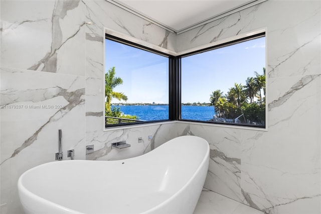 bathroom featuring tile walls, a water view, and a tub to relax in