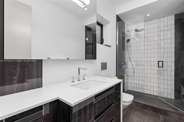 bathroom with vanity, a tile shower, toilet, and tile patterned floors