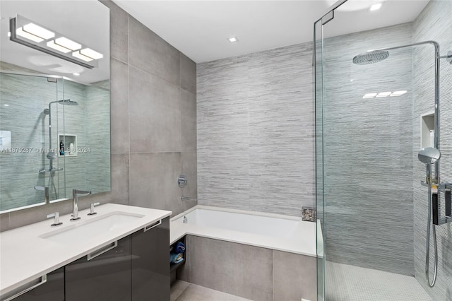 bathroom with tile walls, vanity, and shower with separate bathtub