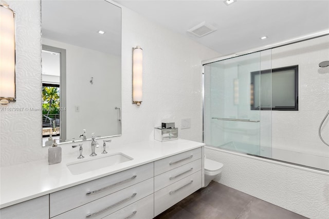 full bathroom featuring vanity, bath / shower combo with glass door, and toilet