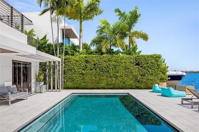 view of swimming pool featuring a patio area and a water view