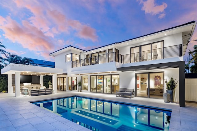 rear view of house with area for grilling, an outdoor hangout area, a balcony, an outdoor bar, and a patio