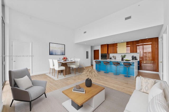 living room with a high ceiling and light wood-type flooring